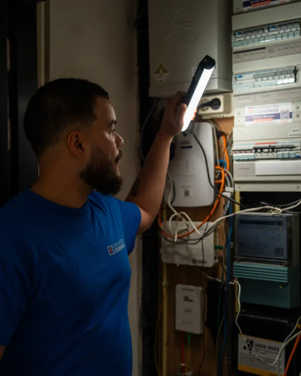 Elektricien zoekt met een lamp naar een storing in de meterkast